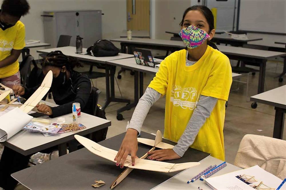 A camper works on her wooden airplane